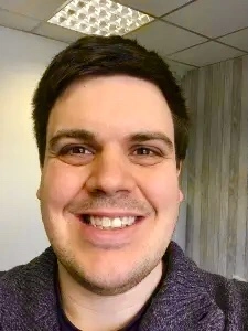 Profile photo of Steve Howey (Counsellor). Steve has dark hair and eyes, and is smiling face on towards the camera. Steve is wearing a grey jumper, with a black T-shirt underneath.